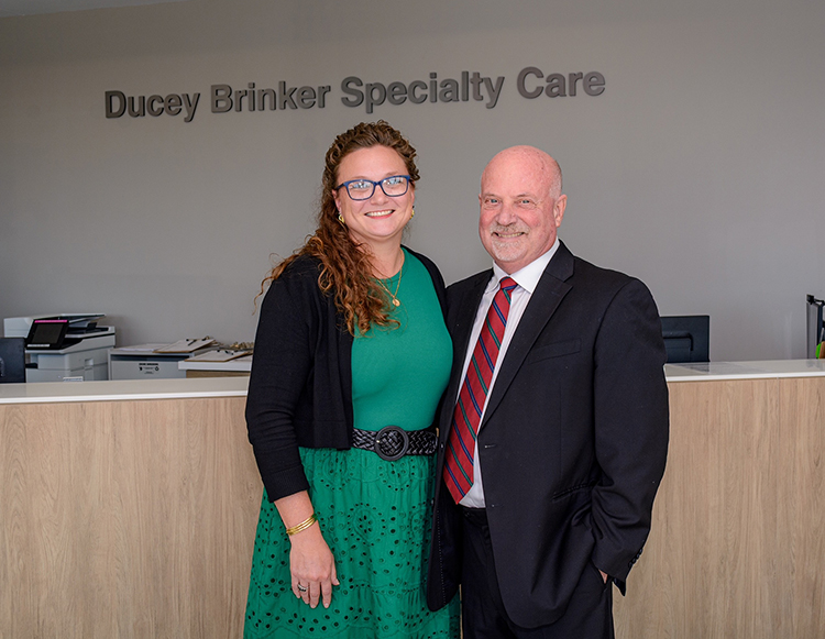 Amanda Brinker and Bill Ducey, MD posing in front of their named space at Reid Health Connersville.