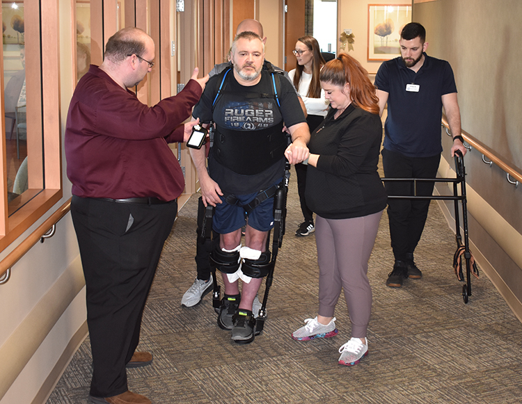A Reid Health patient using the exoskeleton suit with members of the Reid Rehabiliton team