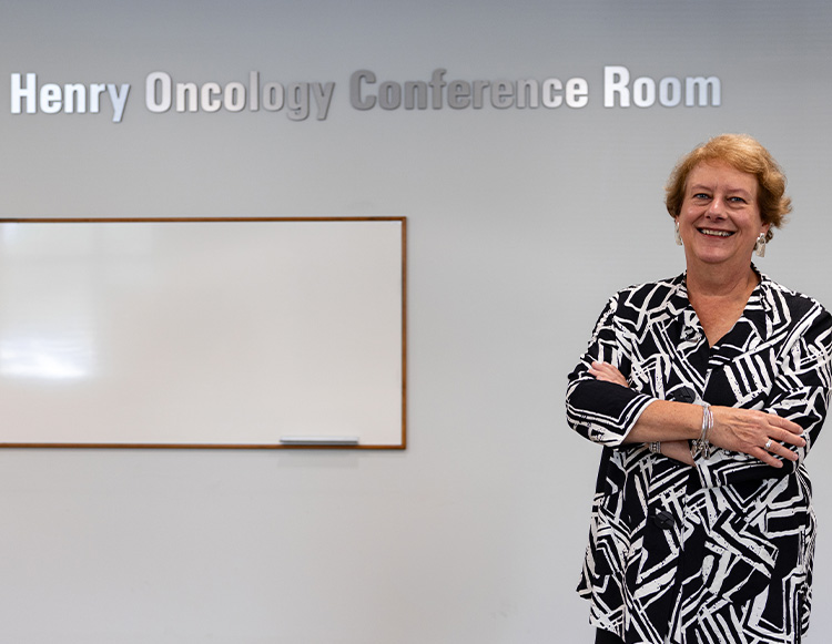 Robin Henry posing in front of the Henry Oncology conference room named space.