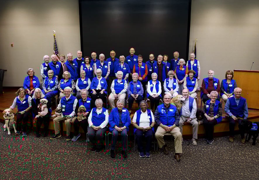 Photo shows the Blue Brigade volunteers at Reid Health. It is a group photo that includes our junior and adult volunteers, but also a therapy dog. 