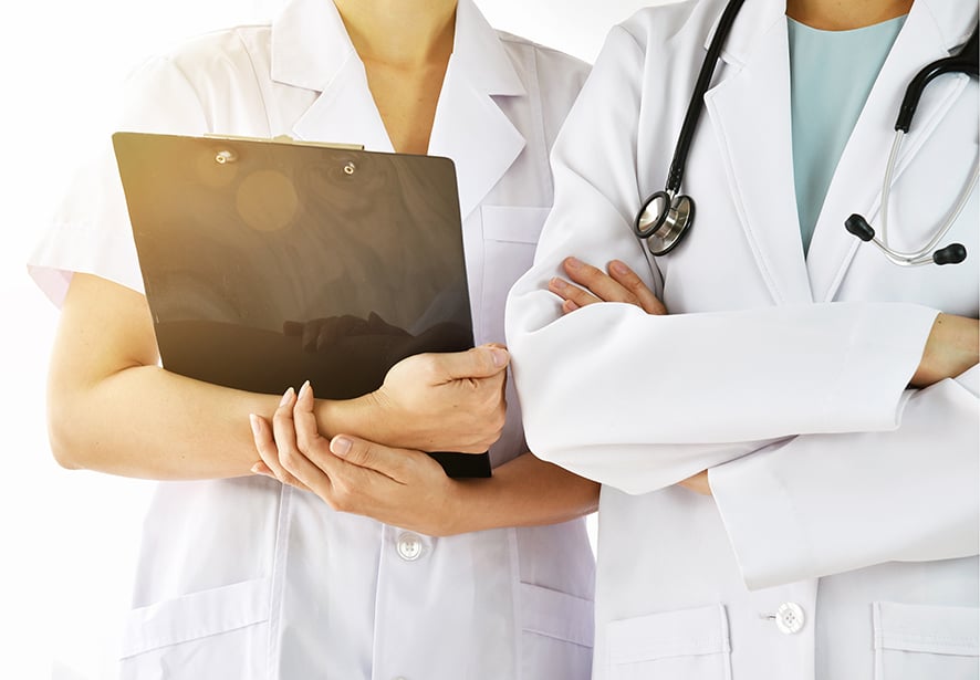 Two medical providers standing together, one wearing a stethoscope and one holding a clipboard.