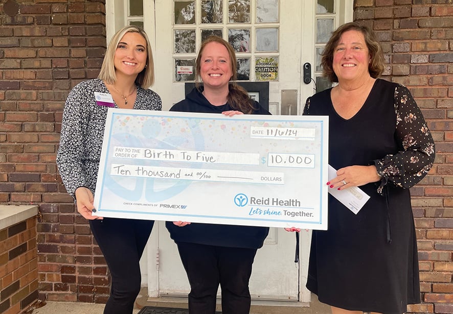 A member of Reid Health Community Engagement team presenting a check to Birth to Five 