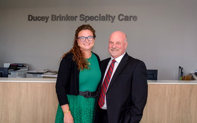 Amanda Brinker and William Ducy, MD posing in front of their named space at Reid Health Connersville Specialty Care