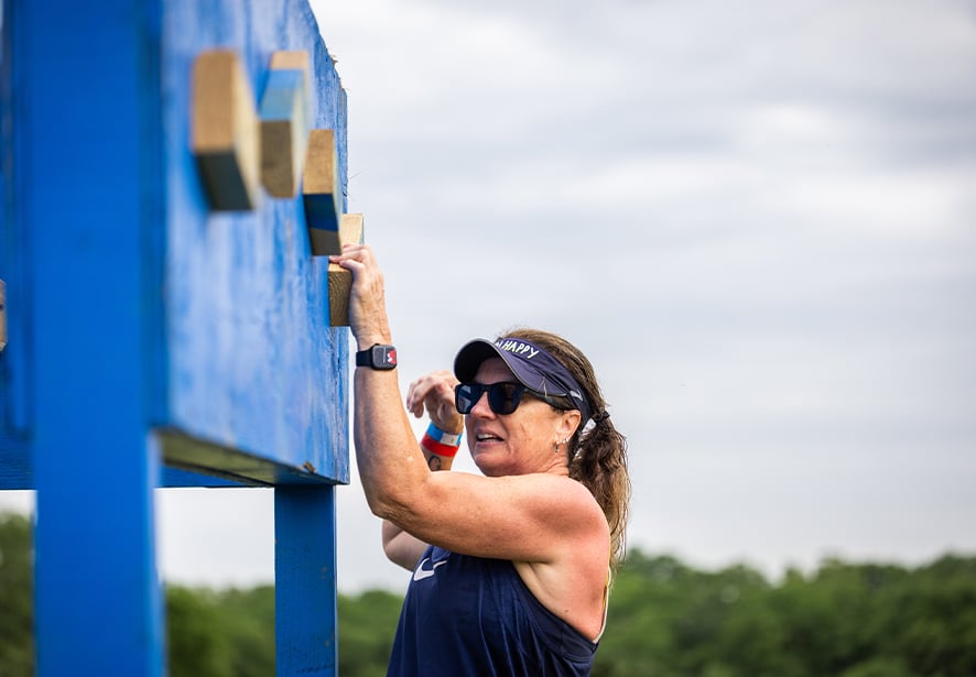 A white adult female navigating one of the obstacles at Reid Adventure Course