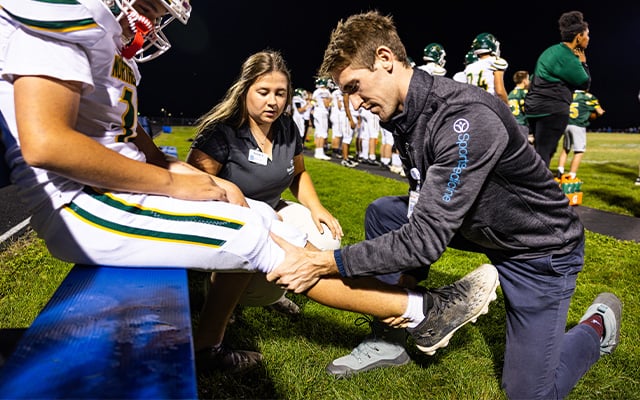 Reid Health's Connor Hoban, MD and Hannah Cupp, ATC working on an athlete together.