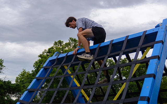 A white teenage boy crossing over an obstacle course at Reid Adventure Course 