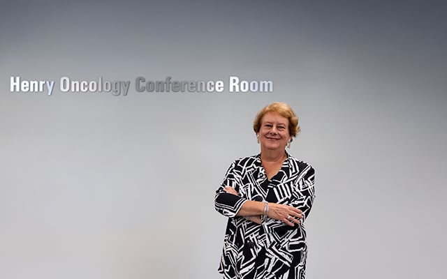 Robin Henry posing in front of the Henry Oncology Conference Room sign