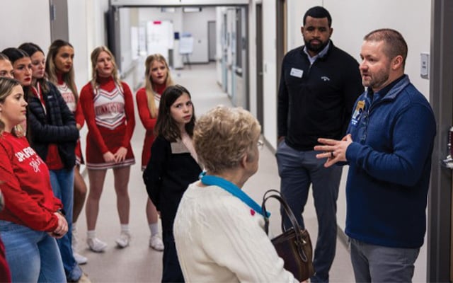 People stand around a Reid Health employee in a hallway at the Reid Health Connersville campus and listen as he talks.   