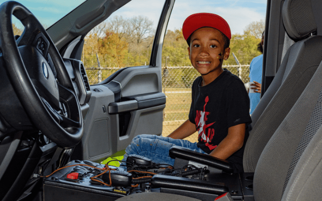 Photo is of a young person in the community engaging with a Reid Health ambulance as part of a Touch a Truck event. 