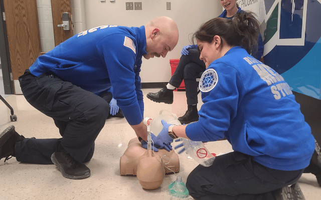 Photo is of two members of the Reid Health EMS Paramedic Program performing a CPR training exercise on a dummy doll.