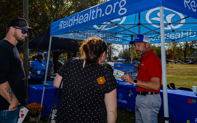 Reid Health Vice President Jason Troutwine speaking with a man and woman at the Connersville Big Build Bash