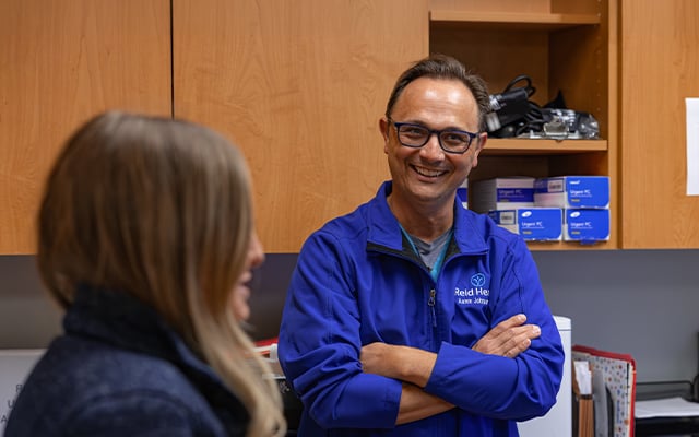 Reid Health Urologist, Aaron Johnson, MD smiling while talking with a member of his staff
