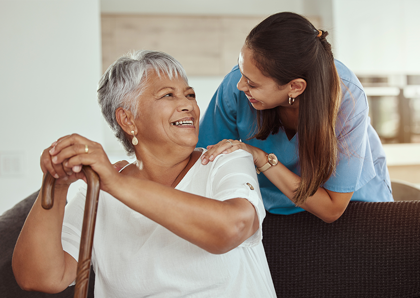 Provider smiles and speaks with patient holding a cane