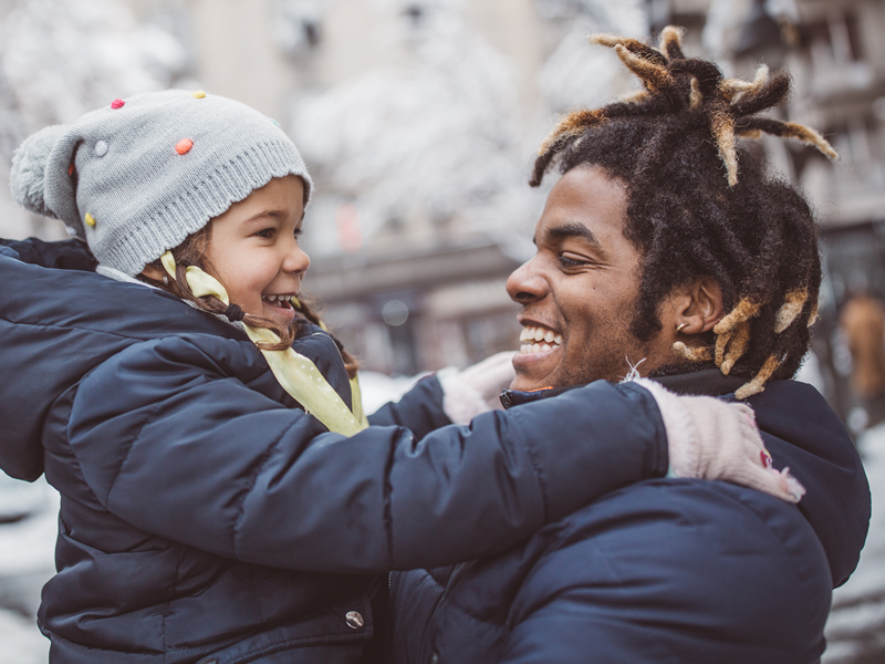 Family outside in the snow smiling at each other 