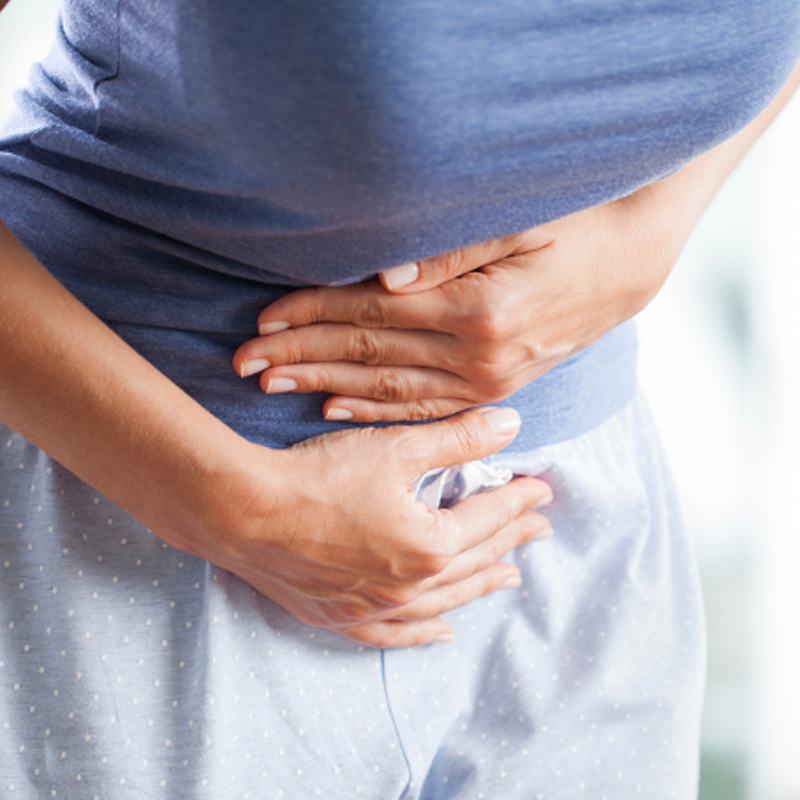 A woman holding her stomach bent over in pain