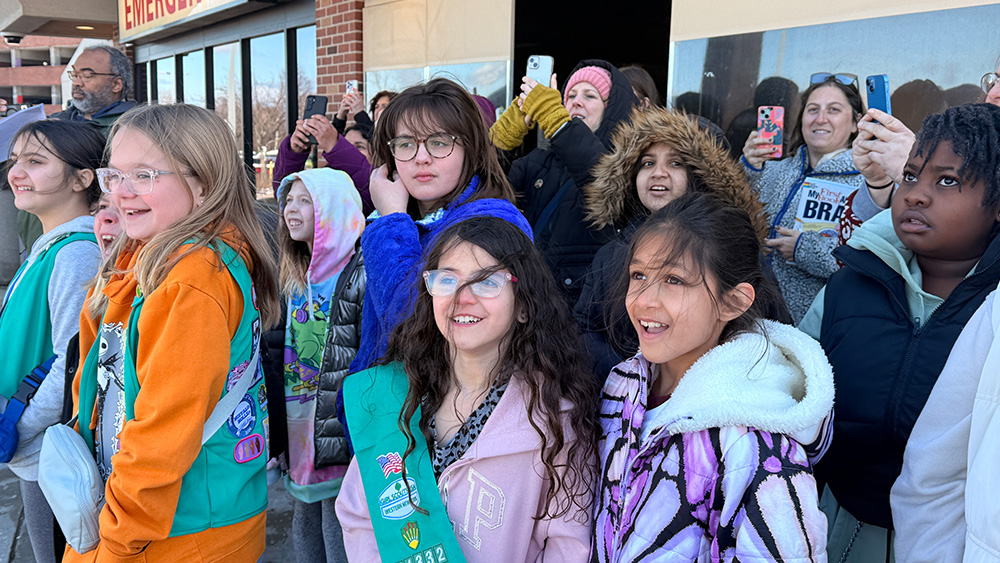 Group of smiling Girl Scouts standing outside hospital emergency room