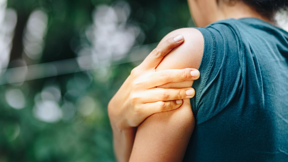 Woman holding left shoulder with her right hand