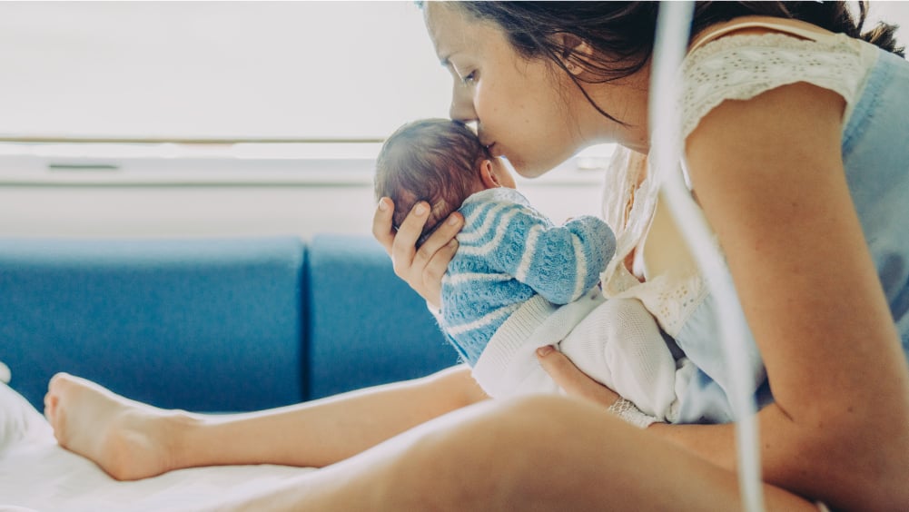 Mother kisses newborn baby