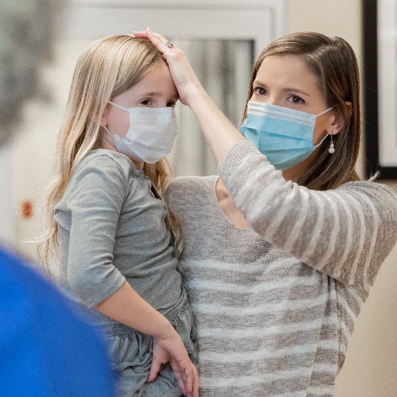 Mother explains young daughter's fever and symptoms to a pediatrician at hospital