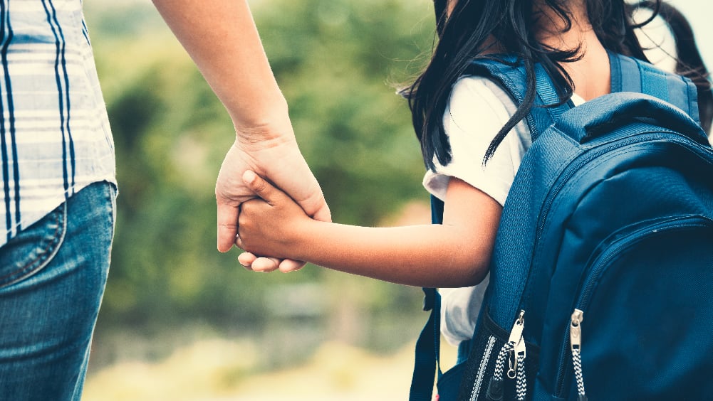Young girl holding hands with mother while walking to school