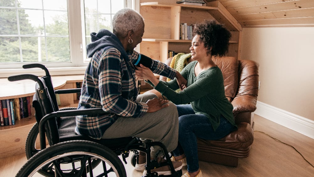 older black adult in wheel chair with young black adult in armchair