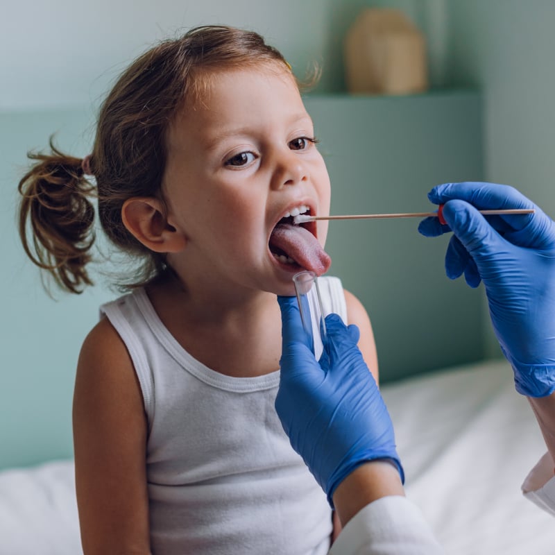 A young White girl gets a throat swab from a physician
