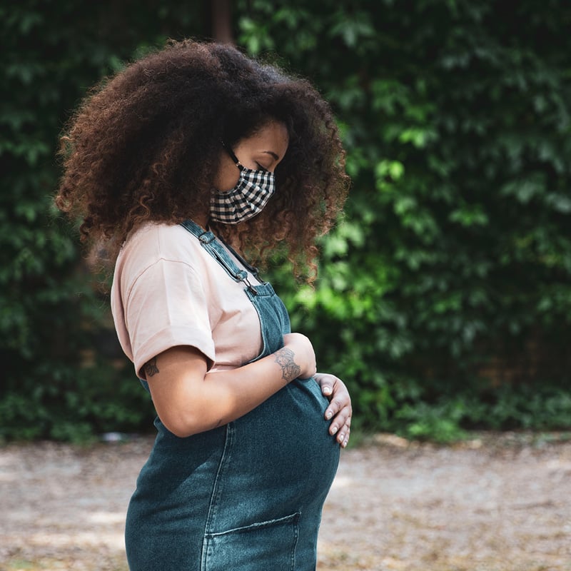 Black pregnant woman stands and looks at the fetus growing in her stomach