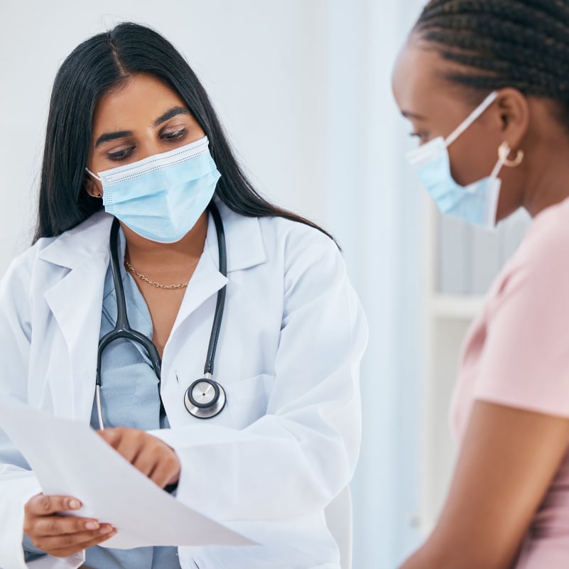 A female medical professional and female patient discuss test results on a paper