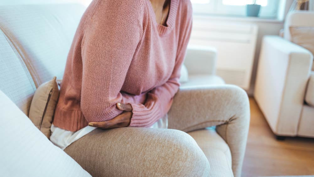 A woman clutches her stomach in discomfort