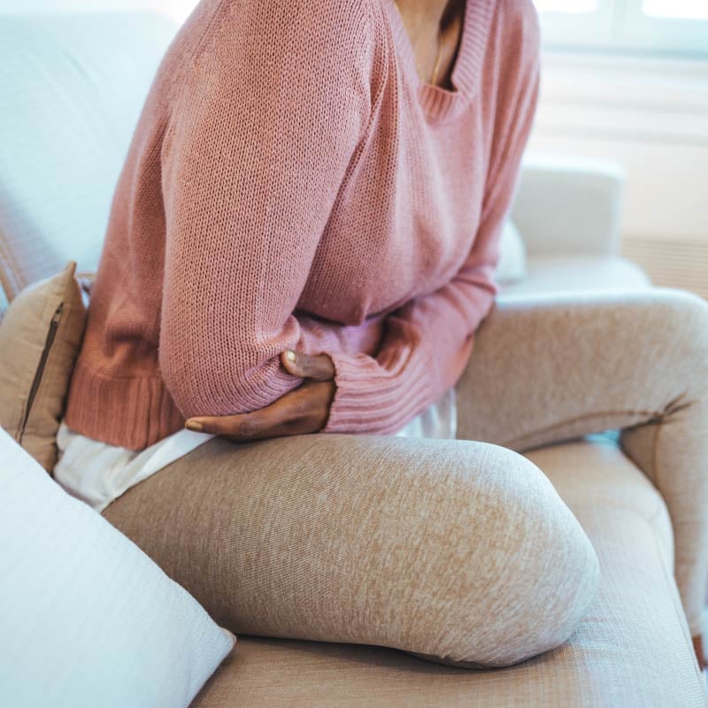 A woman clutches her stomach in discomfort