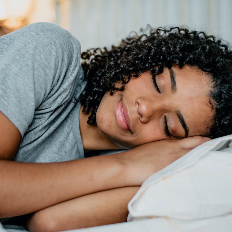 A Black woman lies asleep on a pillow