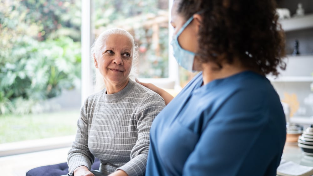 An older Black woman talks with a younger Black woman