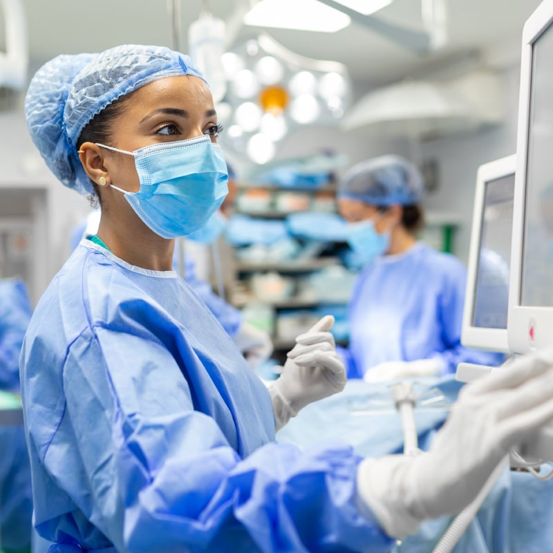 A Black female surgeon looks at a computer in an operating room