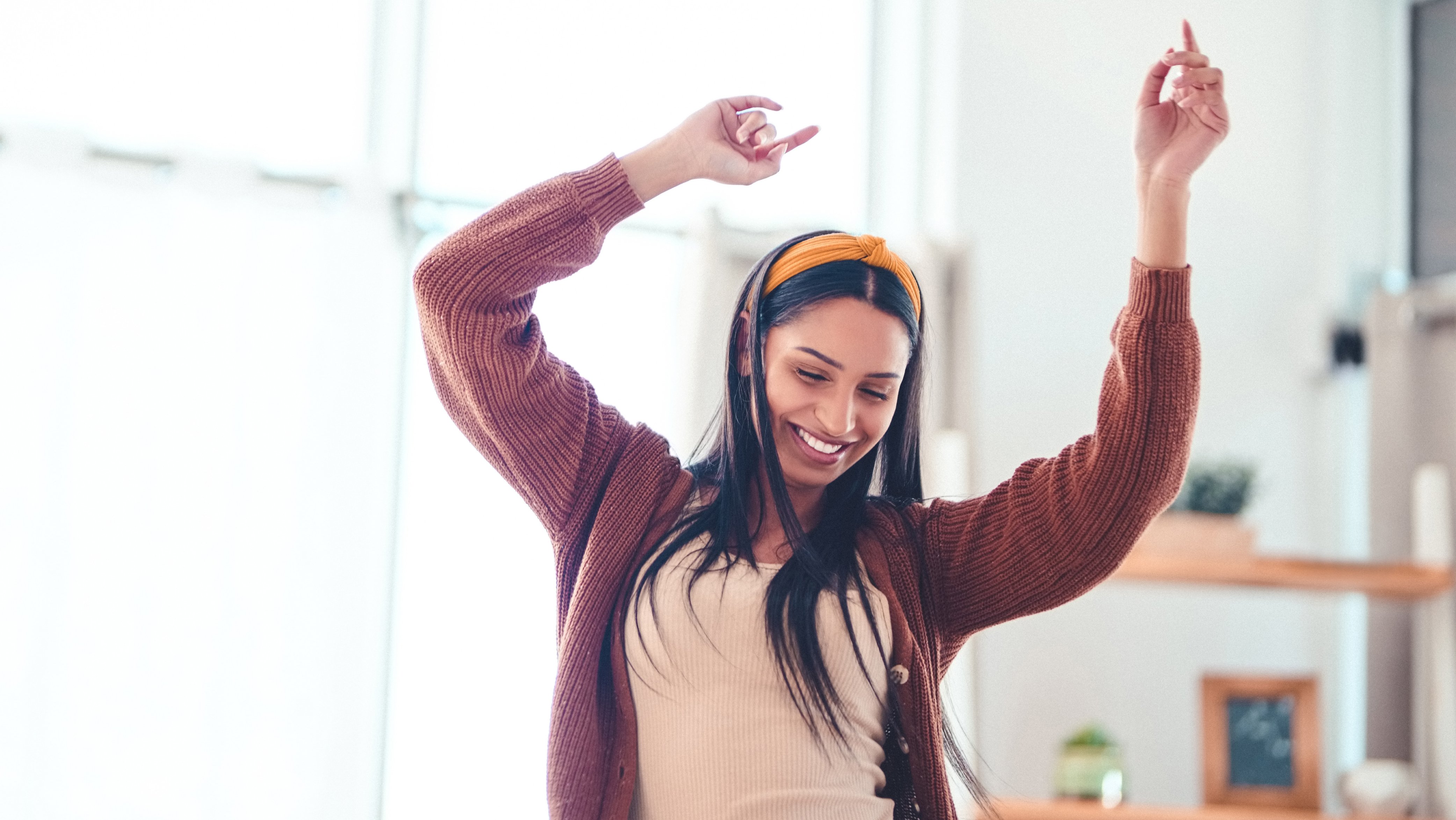 A young woman dances with her hands in the air while smiling