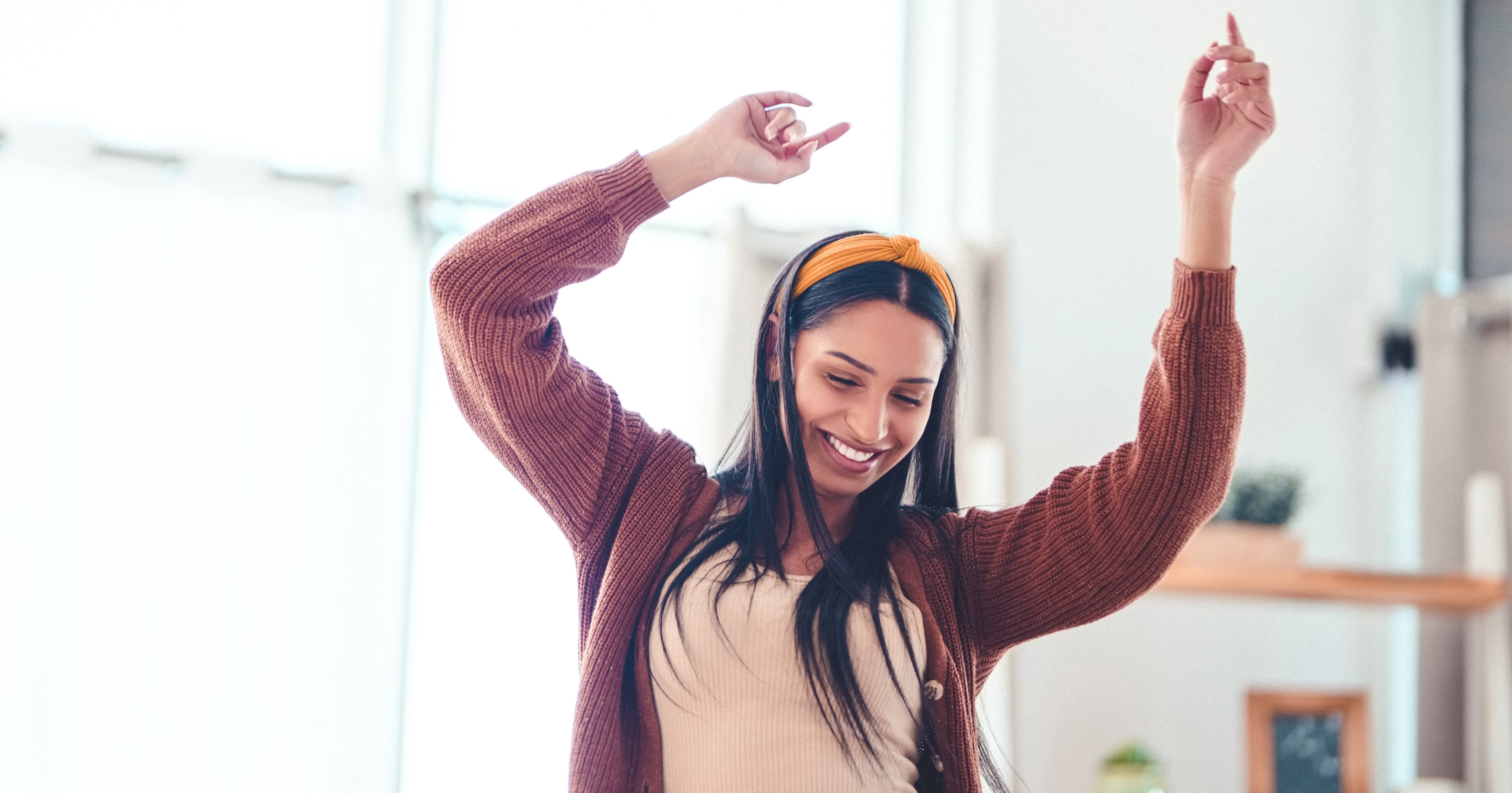 A young woman dances with her hands in the air while smiling