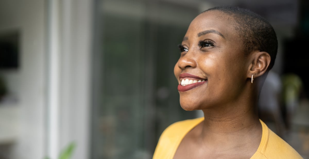 A Black woman smiles out a window