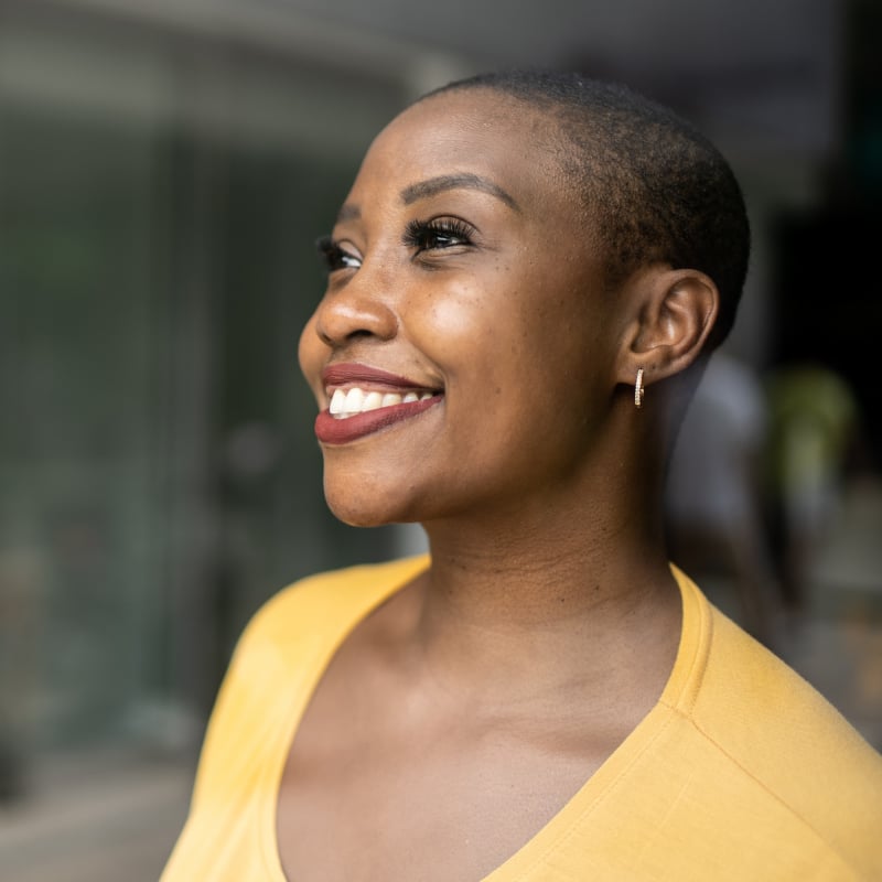 A Black woman smiles out a window