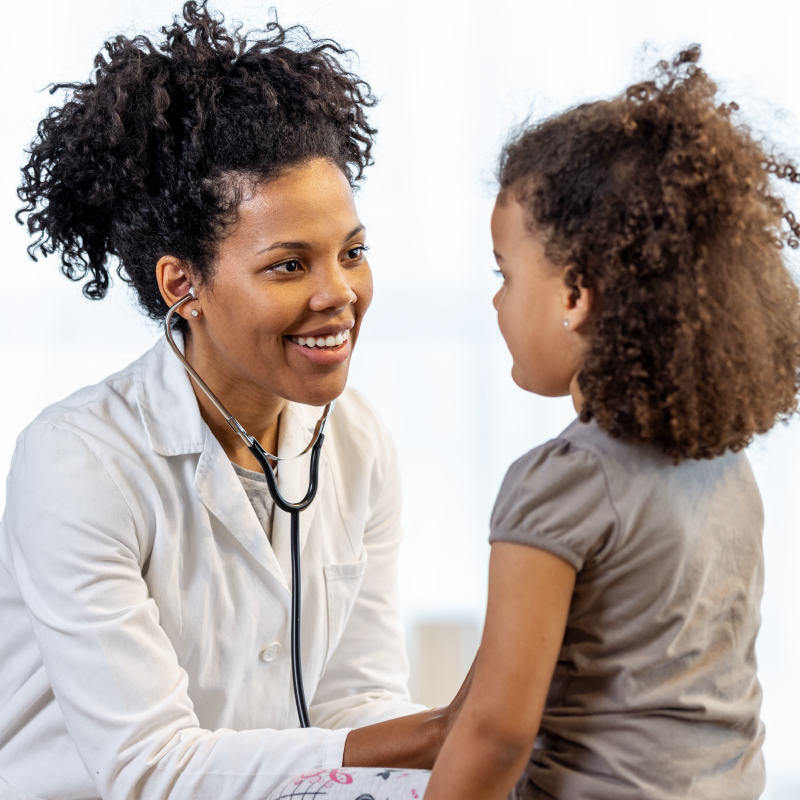 A Black pediatrician meets with a young Black girl
