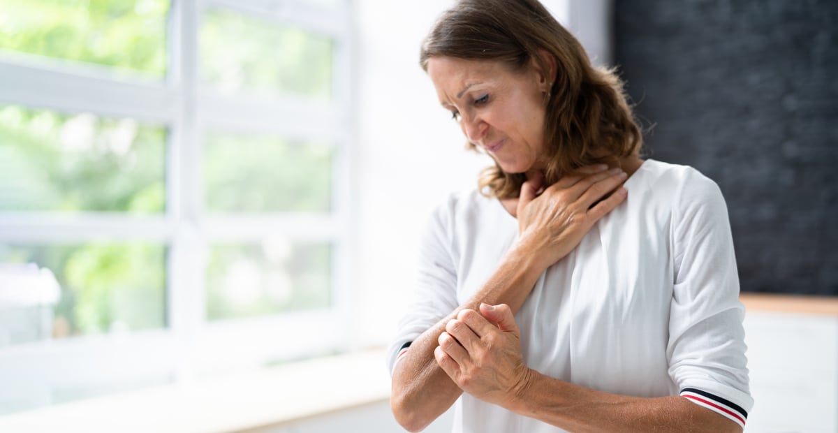A White woman itches at a patch of shingles rash on her arm