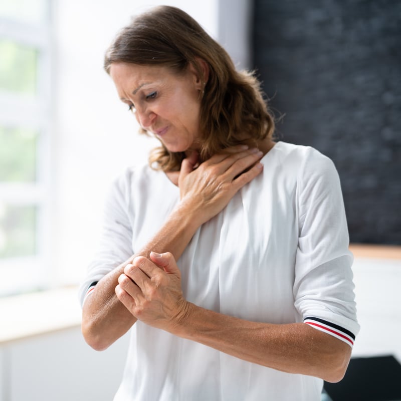 A White woman itches at a patch of shingles rash on her arm
