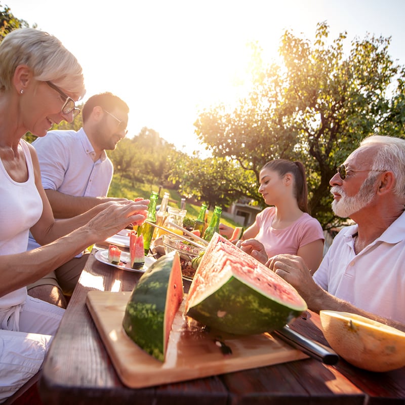 A White family eats outside on a picnic table in summer