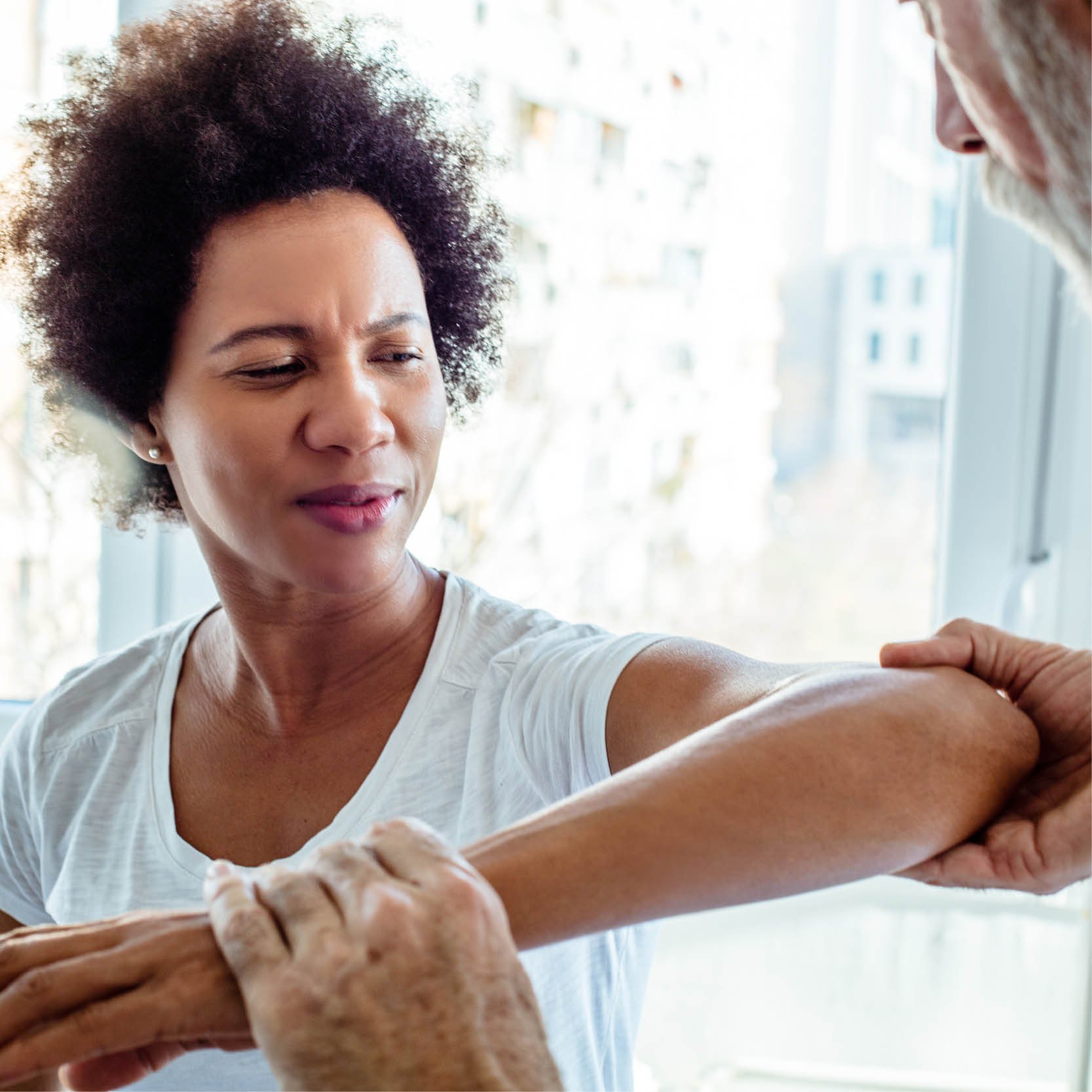 A woman has her elbow examined by a doctor