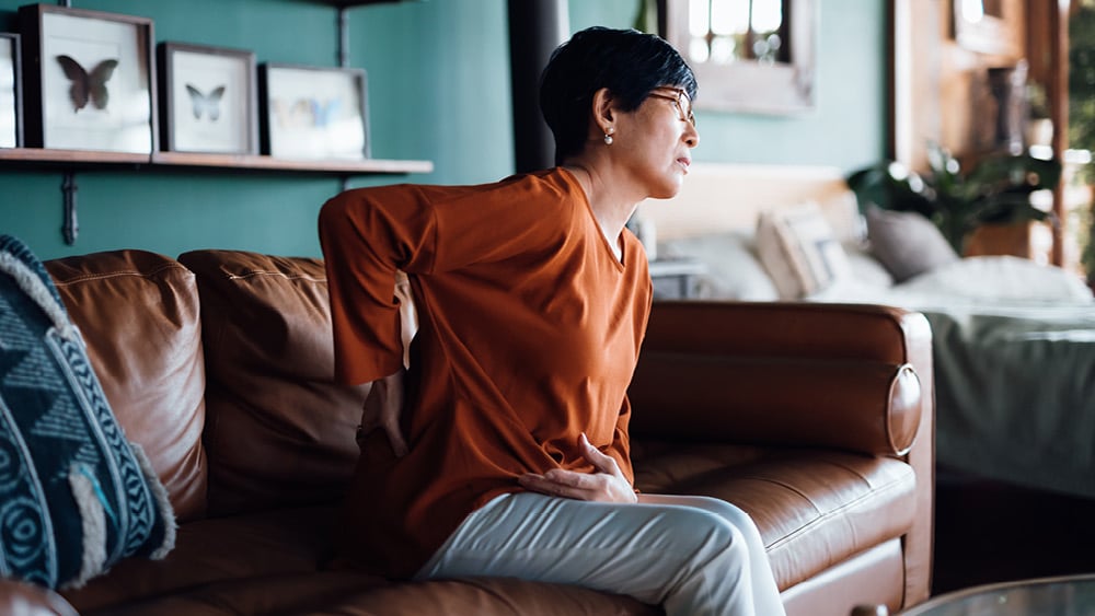 A woman touches her lower back in pain