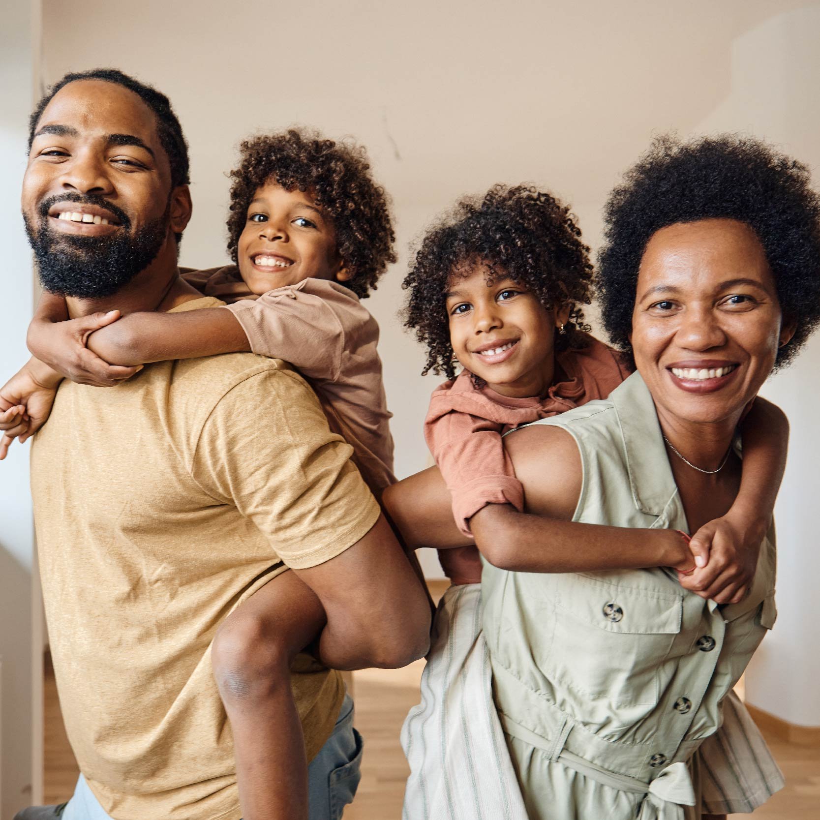 A Black man, woman, and two young children smiling