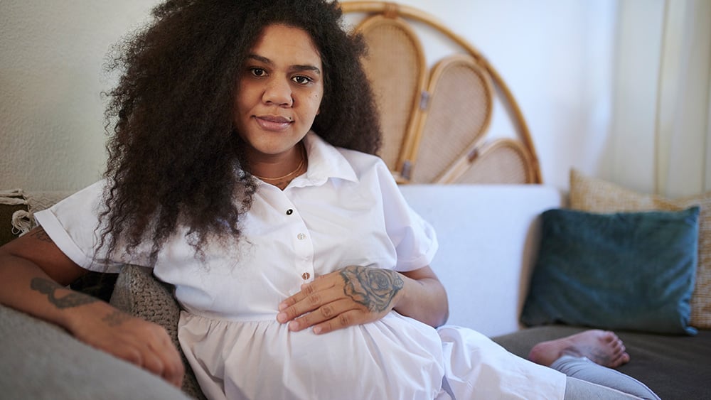 Sofa, mother and portrait of pregnant black woman in living room for relax, rest and calm at home. Family, pregnancy and face of happy mom with hand on stomach for care, hope and love for future baby