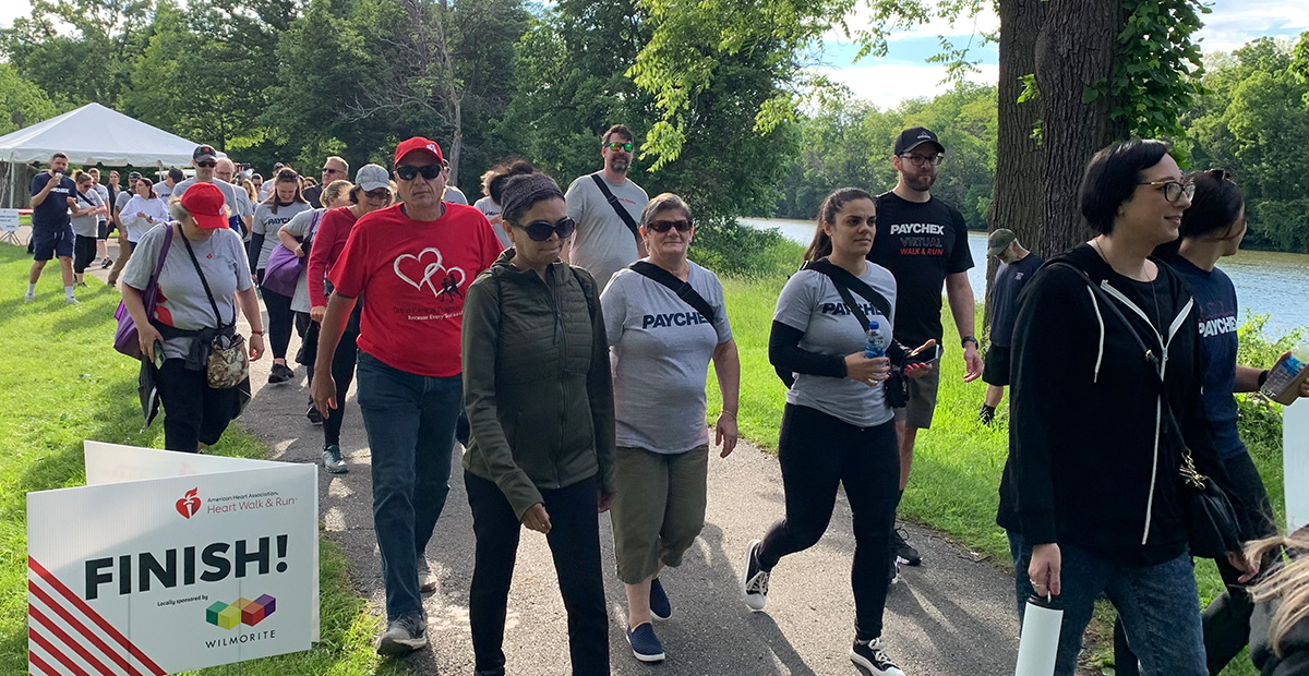 Group of people in long sleeved shirt and pants walk on a sidewalk outside