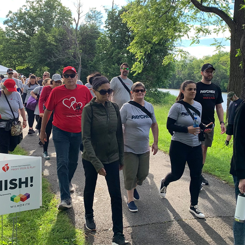 Group of people in long sleeved shirt and pants walk on a sidewalk outside