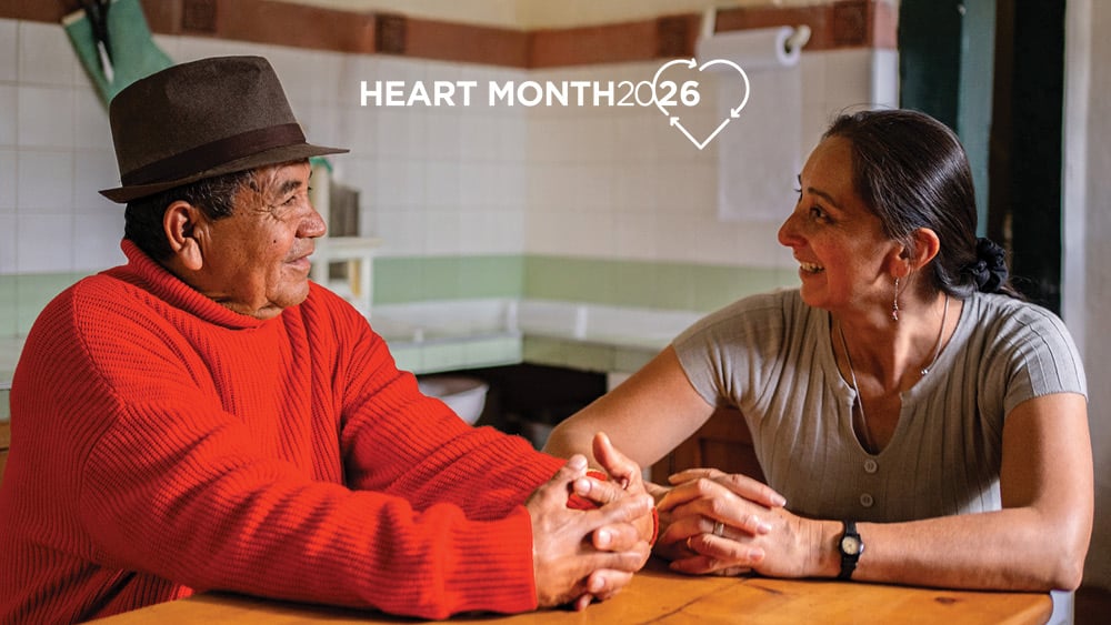 Older father and adult daughter talking at kitchen table