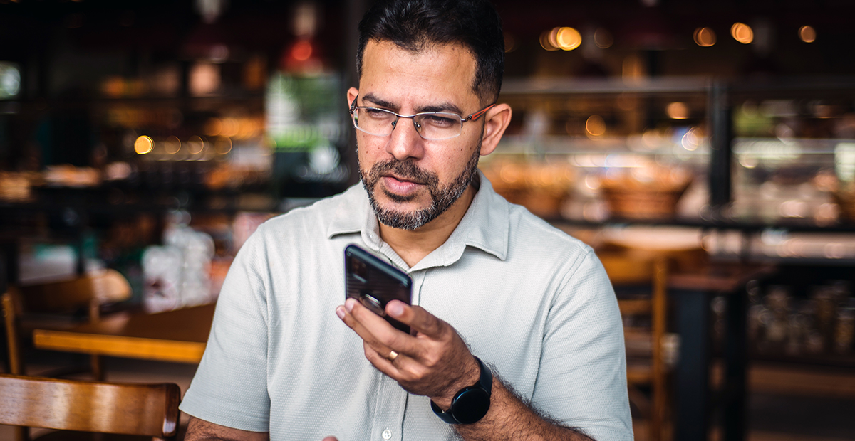 Latino man wearing glasses and short sleeve button down shirt talks into phone