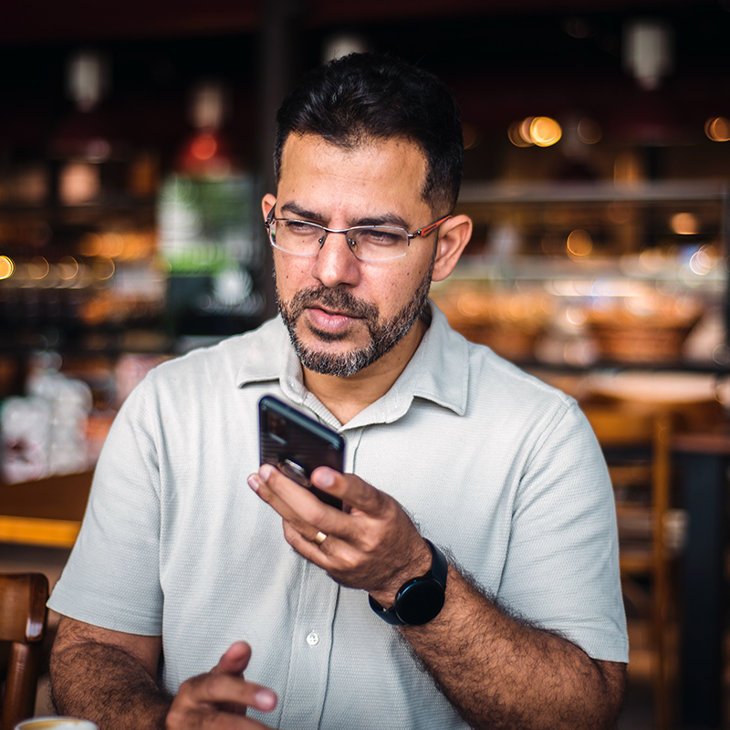 Latino man wearing glasses and short sleeve button down shirt talks into phone